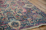 Blossomed floral motifs in blush, navy blue, and ivory on a circa 1940s Persian Kerman rug.