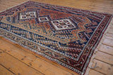Hand-knotted Afshar rug with diamond medallions and floral botehs in navy, rust, and beige.