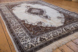 An angled view of the vintage Tabriz carpet's shield medallion and intricate brown borders.