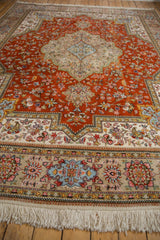 White fringe and vibrant floral motifs along the beige Tabriz rug border.