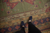 Vintage Stone Wash Dhurrie carpet's olive green field with geometric plants and raspberry red patterns.