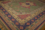 Corner section of vintage Dhurrie carpet with geometric olive, raspberry, and navy motifs.