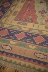 Dhurrie rug border with navy, raspberry, and olive geometric motifs, showing fringe.