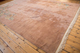 Side angle of a vintage Japanese carpet's plush, dusty rose pile and sprawling floral corners.