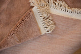 Plush dusty rose pile and flat woven reverse of a vintage carpet corner with ivory fringe.