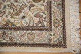 A vintage Tabriz rug corner with plush ivory pile, detailed floral patterns, and intact fringe.
