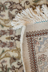 The fine hand-knotted back and plush ivory pile of a vintage Persian Tabriz rug corner.