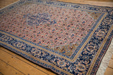 Dusty rose Herati field, indigo border, and gold spandrel of a vintage Ardebil carpet.