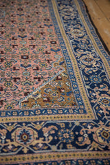 Vintage Ardebil carpet corner showing dusty blush field, Herati motif, and gold, navy border.