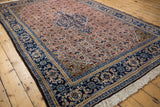 Ardebil rug corner: navy blue scrolling border, gold spandrel, and dusty blush Herati field.