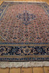 Close-up of vintage Ardebil carpet's cream fringe and indigo blue traditional border design.