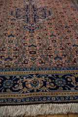 Hand-knotted ivory fringe and richly detailed indigo blue floral border.