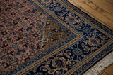 Vintage Ardebil rug corner displaying dusty blush Herati field, golden spandrel, and indigo border.