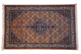 Vintage Persian Ardebil carpet featuring a dark blue diamond medallion and rust Herati motif field.