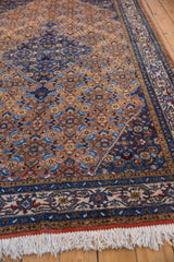 Vintage Persian Ardebil rug with white fringe, intricate blue-beige borders, and rust Herati motif.