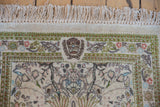 Ivory fringe and intricate border of a vintage Tabriz rug with vinery, green, and blush motifs.