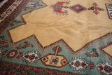 Vintage Meshkin rug detail: pale ochre field, teal border with geometric and floral motifs.