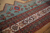 Ocean green geometric motifs against ivory and rust patterned borders on a vintage Meshkin rug.