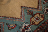 Vintage Meshkin carpet: gold and teal fields, stepped border, and stylized finned motif.