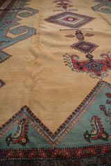 Pale ochre field of vintage Meshkin carpet, revealing teal geometric and rust rams horn design motifs.