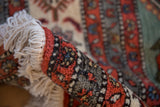 Vintage Meshkin carpet, close-up of rolled edge with ivory fringe and geometric pile.