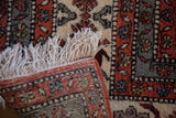 Vintage Meshkin carpet detail with ivory fringe, dense rust and green geometric pile, and tightly woven back.