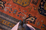 Rust field detail of vintage Ardebil carpet with stylized navy, bronze, ivory birds and animals.