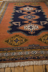 Gul medallion on dusty sandalwood, finned navy blue patterns, intricate border, and fringe.