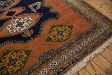 Vintage Meshkin carpet corner, featuring white fringe, geometric borders, and a golden finned gul medallion.