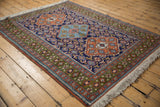 Vintage Ardebil rug corner with deep green floral border, terra cotta motifs, and ivory fringe.