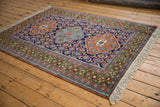 Vintage Ardebil rug corner showing cream fringe and patterned green and rust borders.