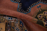 Deep pile texture of a folded Ardebil carpet with dusty sandalwood and navy blue finned design.