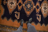 Deep navy and gold finned geometric patterns on Vintage Ardebil carpet, with boots.