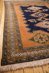 Intricate patterned borders in deep navy blue, sandalwood, gold, and ivory on a vintage Ardebil carpet corner with fringe.