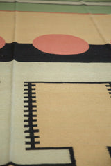 Detail of a vintage Indian kilim's abstract geometric pattern in beige, deep blush, black, and green.