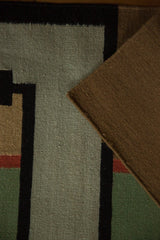 Hand-woven kilim showing reverse side, original selvage, and beige, green, black patterns.