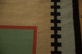 Hand woven vintage Kilim rug corner showing beige, mallard green, cherry red, and stepped black geometric design.