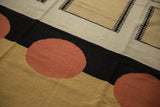 Interlocking cinnabar red circles, black bands, and beige geometric motifs on the contemporary Kilim.