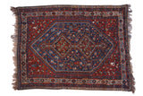 Vintage Shiraz rug with a stepped double diamond medallion in sapphire blue on a red field with geometric motifs.