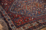 Angled view of a vintage Shiraz rug's corner, highlighting the intricate geometric borders and hand-knotted pile.