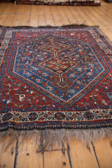Low-angle view of the vintage Shiraz rug's hand-knotted pile, geometric patterns, and short fringe.