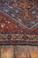 Detailed view of a vintage Shiraz rug's wool pile, showing the geometric border and fringe.