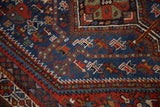 Intricate geometric animal and serpent motifs on the wool pile of a vintage Persian rug.
