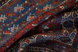 Richly textured pile of a vintage Shiraz rug with geometric animal motifs in red, ivory, and sapphire blue.