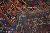 Folded corner of the vintage Shiraz rug showing its colorful pile, hand-knotted back, and fringe.