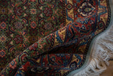 Soft cream fringe and intricate light blue, gold, and rust border on a hand-knotted Bulgarian rug.