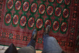 A view from above of the repeating gul medallions on a lustrous, forest green Pakistani Bokhara carpet.
