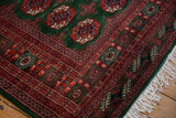 Plush corner of a fine Pakistani Bokhara rug with rust geometric borders and clean ivory fringe.