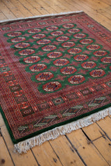 Detailed rust and green geometric border and ivory fringe on a vintage Pakistani Bokhara carpet.