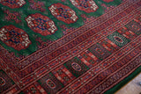 Lustrous wool pile and detailed rust border on a vintage green Bokhara-style carpet.